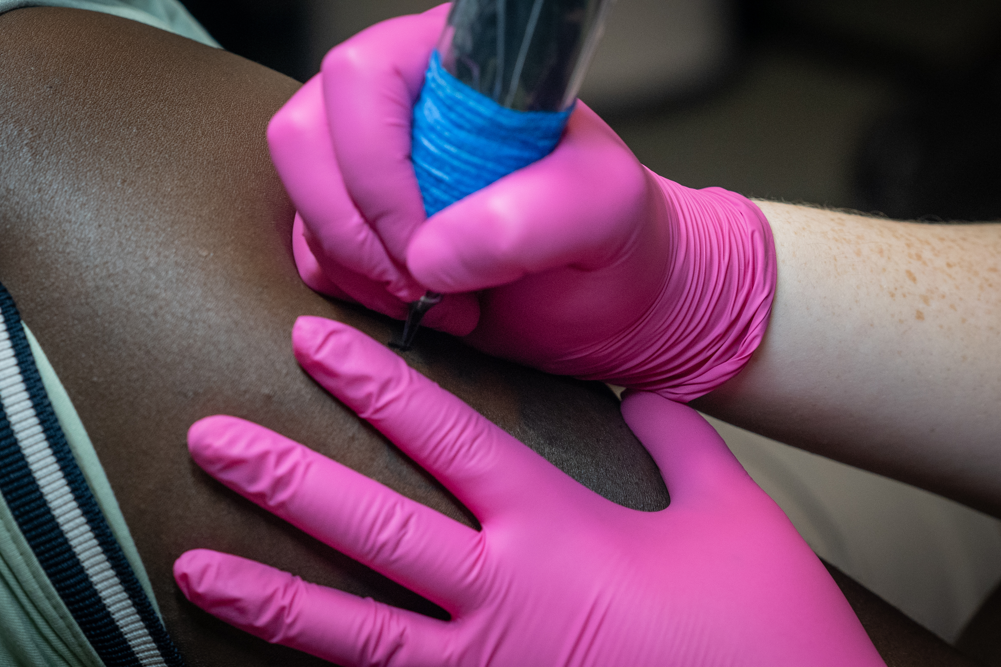 tattoo sessions with a woman tattooing black skin with pink gloves on at tattoo kiss